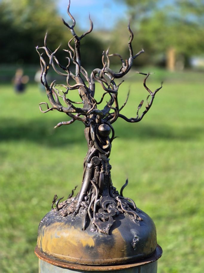 Romain Bresson : le sculpteur métal et son univers science-fiction Sculpture d'un arbre stylisé en métal, tronc et branches entrelacés sur un socle.