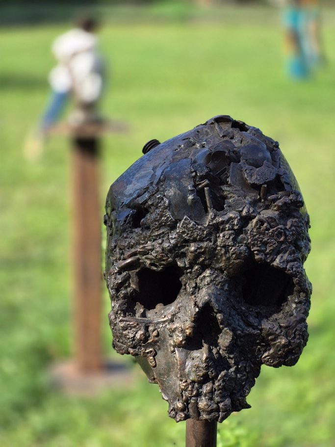 Romain Bresson : le sculpteur métal et son univers science-fiction Sculpture d'un arbre noueux en métal, posé sur un socle circulaire dans un parc.