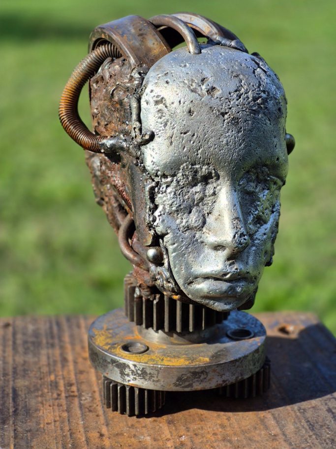 Romain Bresson : le sculpteur métal et son univers science-fiction Sculpture de tête humanoïde en métal, avec détails mécaniques et surface usée.