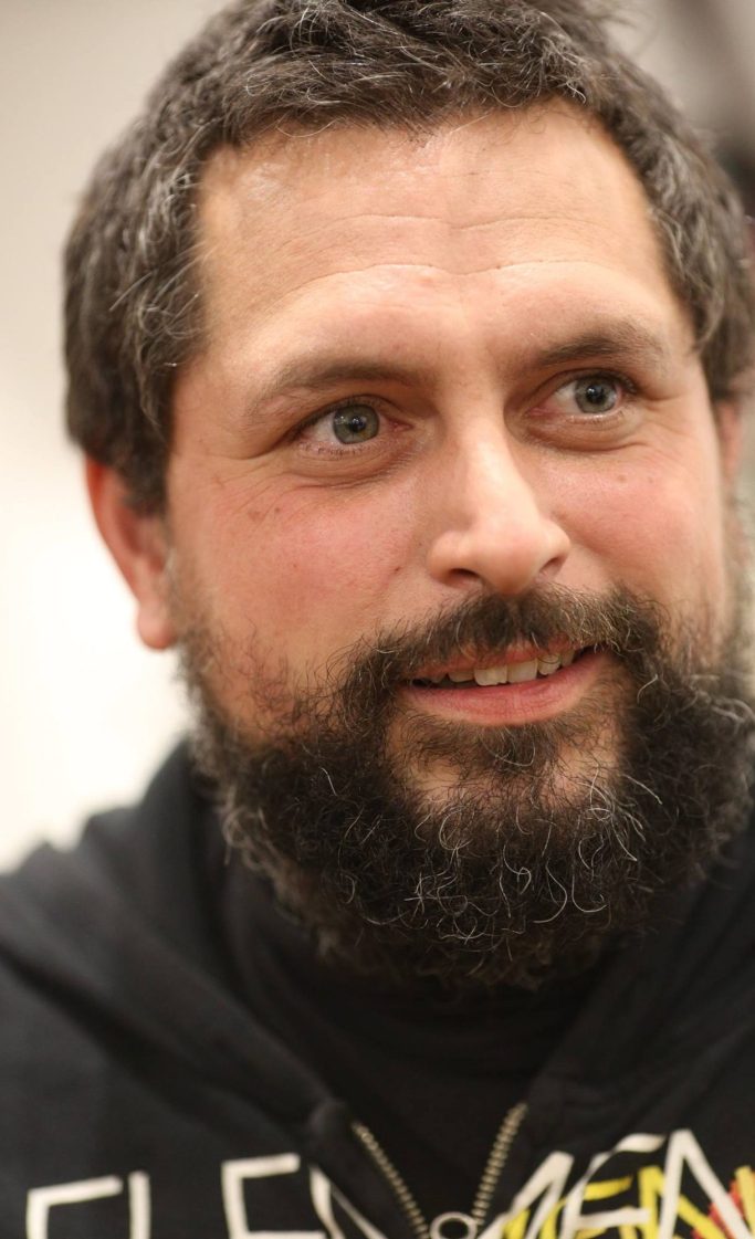 Romain Bresson : le sculpteur métal et son univers science-fiction Homme avec une barbe, souriant, portant un sweatshirt noir.